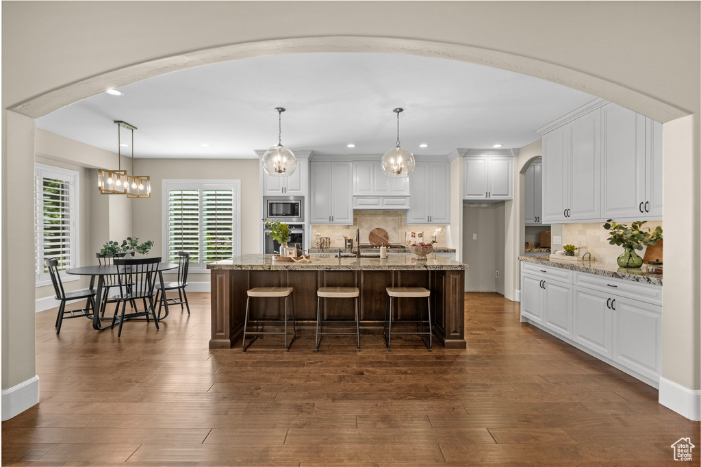 Kitchen featuring appliances with stainless steel finishes, white cabinets, recessed lighting, dark wood-style flooring, and decorative backsplash