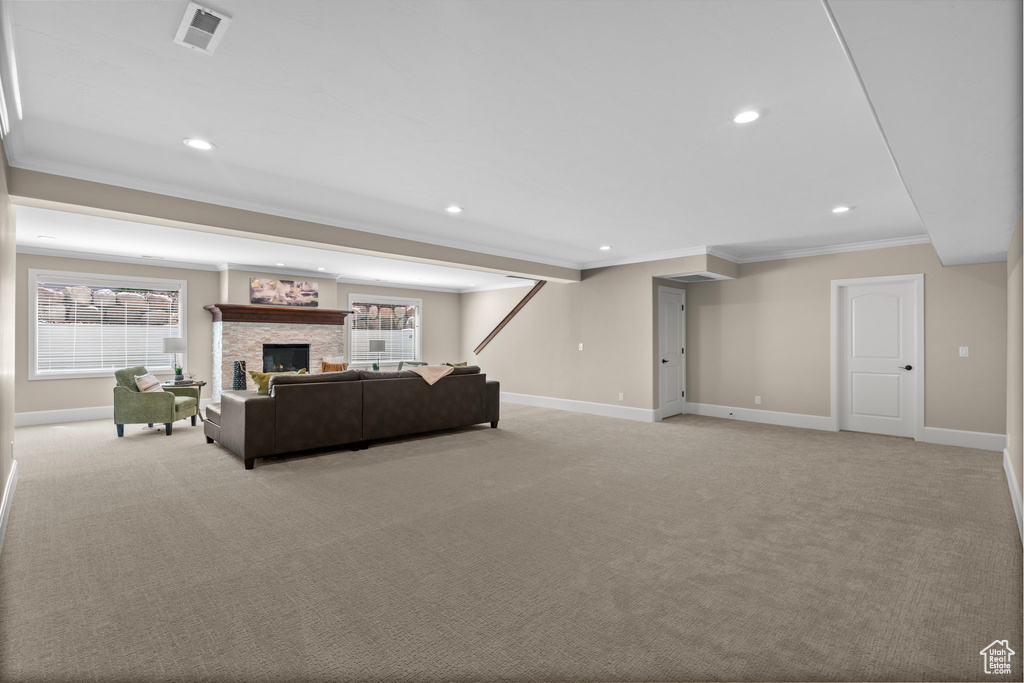 Living area featuring crown molding, light carpet, recessed lighting, healthy amount of natural light, and a fireplace