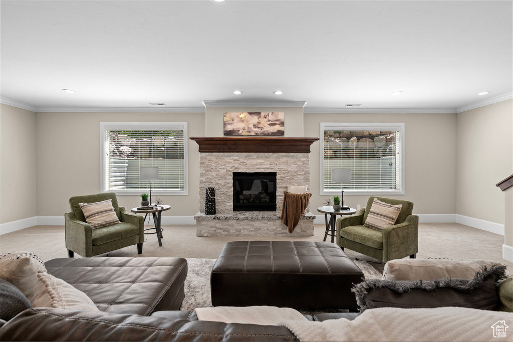 Living area with a stone fireplace, recessed lighting, light colored carpet, and crown molding