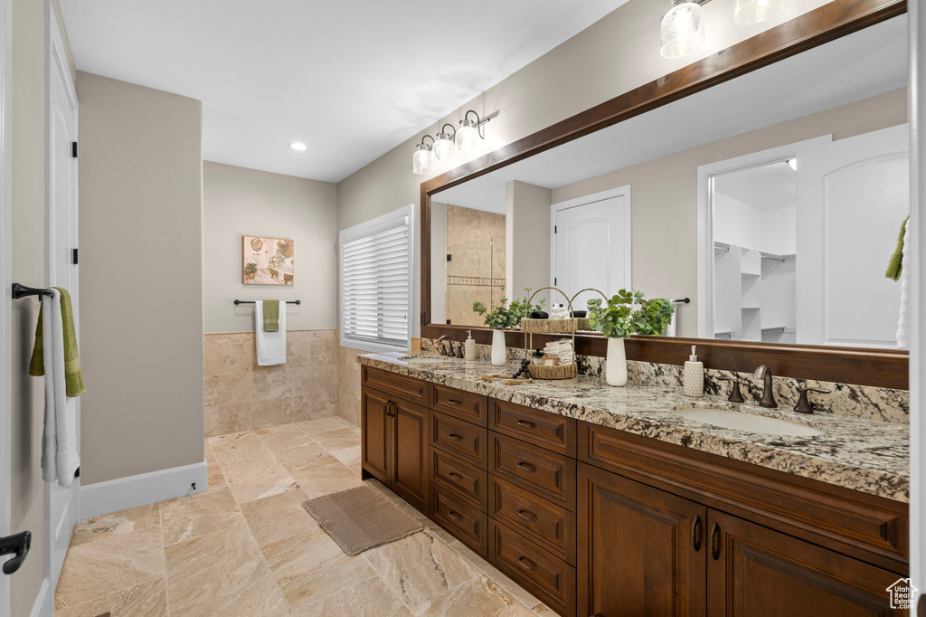 Full bathroom with walk in shower, double vanity, a closet, and wainscoting