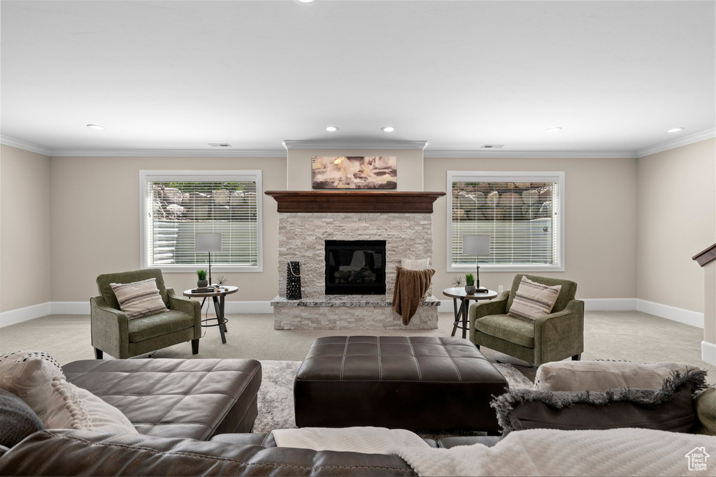 Living room with a stone fireplace, recessed lighting, light colored carpet, and ornamental molding