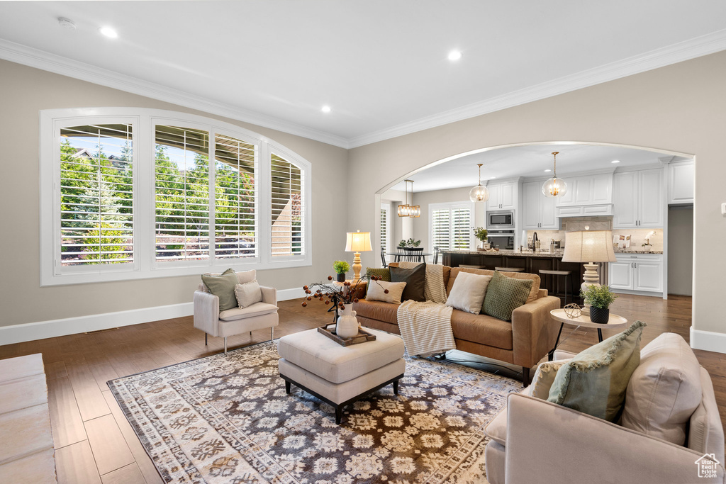 Living room with arched walkways, hardwood / wood-style floors, recessed lighting, and crown molding
