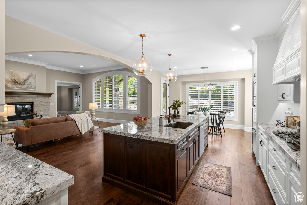 Kitchen featuring arched walkways, dark brown cabinets, white cabinetry, ornamental molding, and recessed lighting