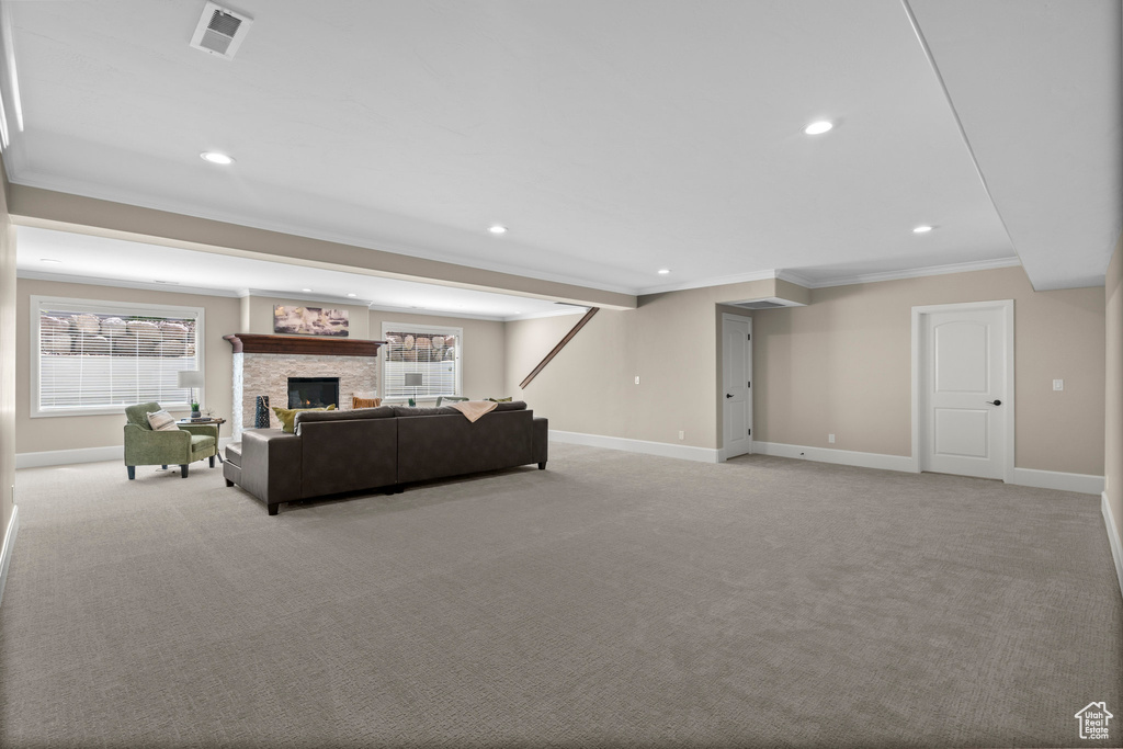 Living room featuring ornamental molding, light colored carpet, recessed lighting, plenty of natural light, and a fireplace