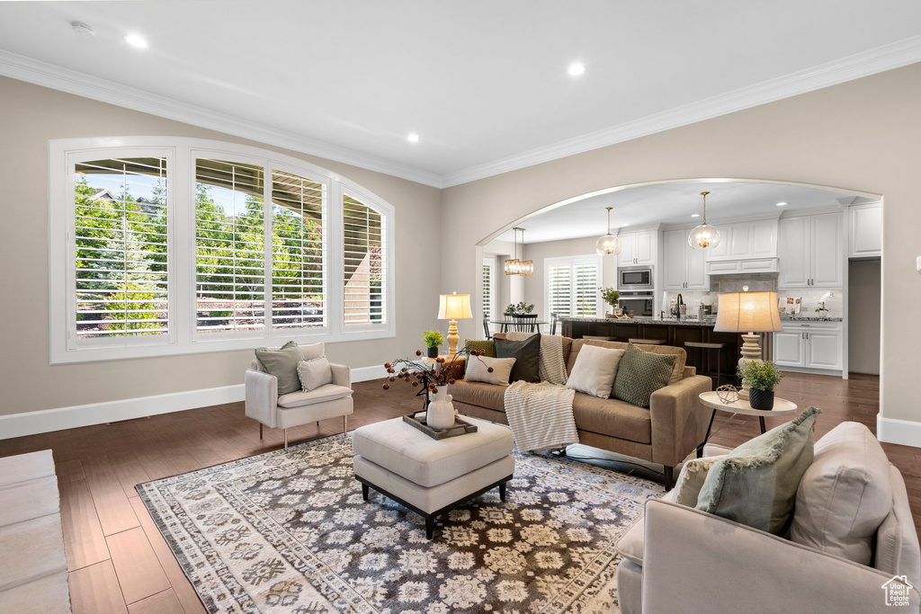 Living area featuring arched walkways, hardwood / wood-style flooring, recessed lighting, and ornamental molding