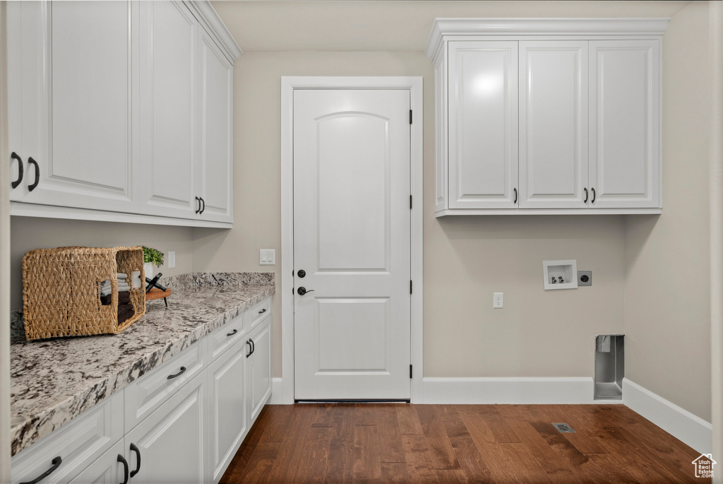 Washroom with cabinet space, dark wood-type flooring, hookup for a washing machine, and hookup for an electric dryer