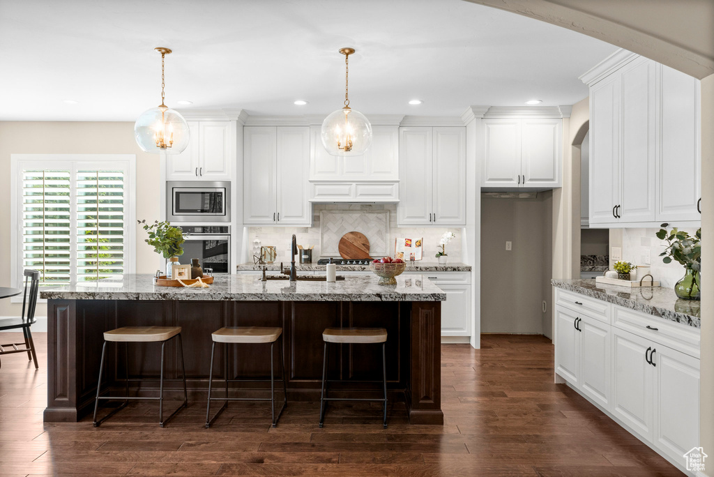 Kitchen with stainless steel appliances, arched walkways, recessed lighting, a breakfast bar area, and tasteful backsplash