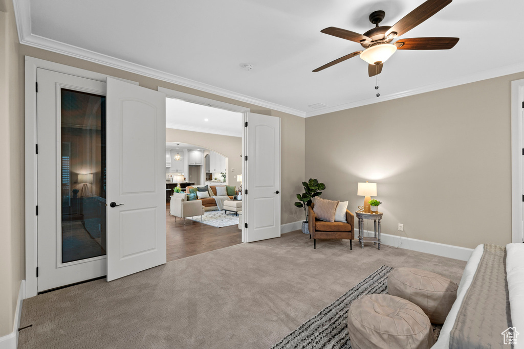 Living area with carpet flooring, ornamental molding, arched walkways, and a ceiling fan