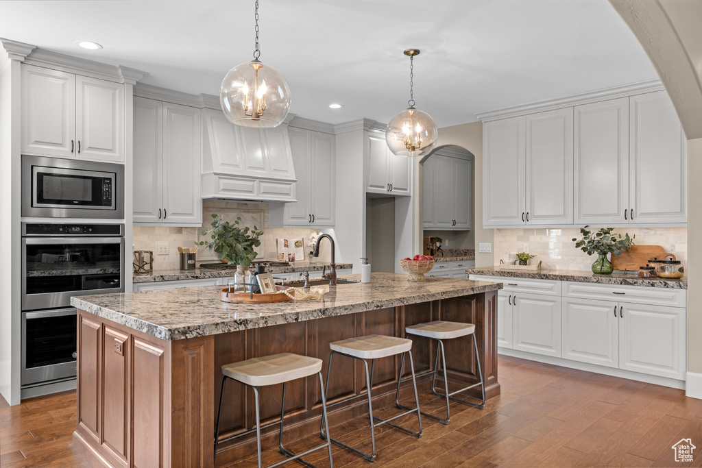 Kitchen with stainless steel appliances, backsplash, recessed lighting, wood finished floors, and arched walkways