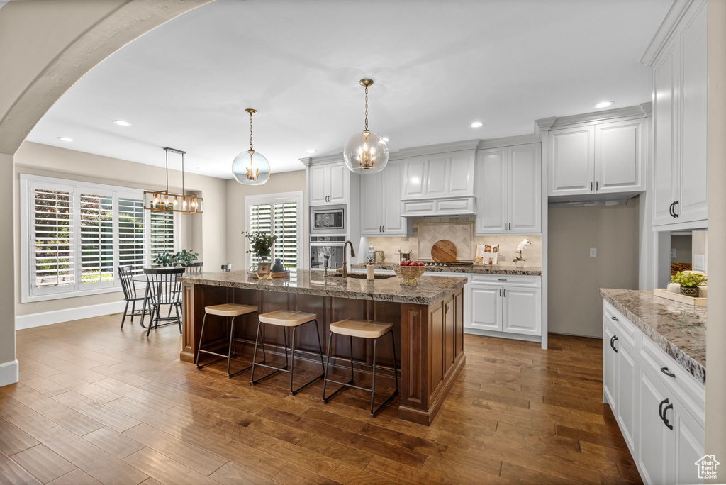 Kitchen with stainless steel appliances, recessed lighting, backsplash, white cabinets, and a kitchen bar