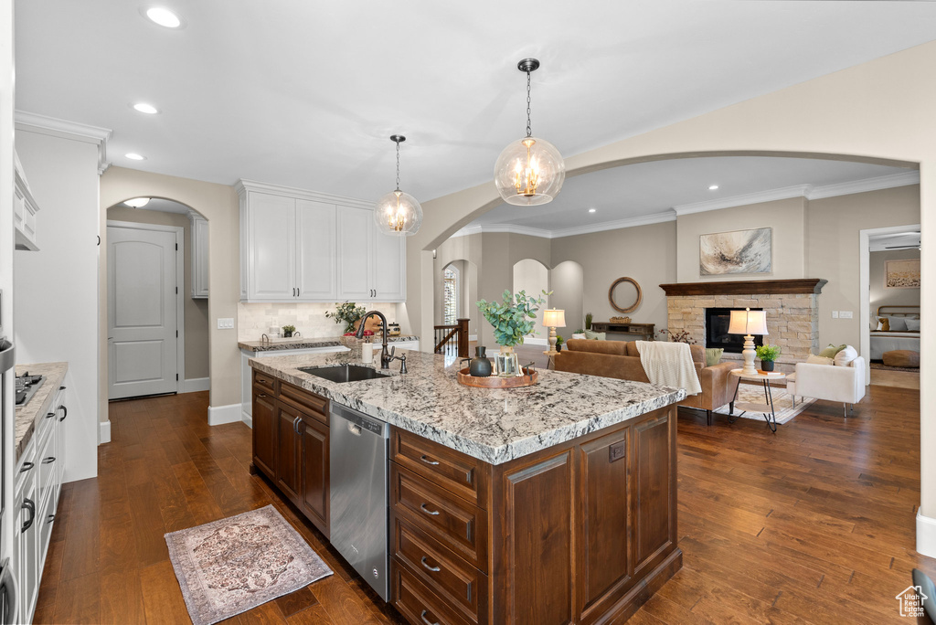 Kitchen featuring dishwasher, arched walkways, white cabinetry, recessed lighting, and a kitchen island with sink