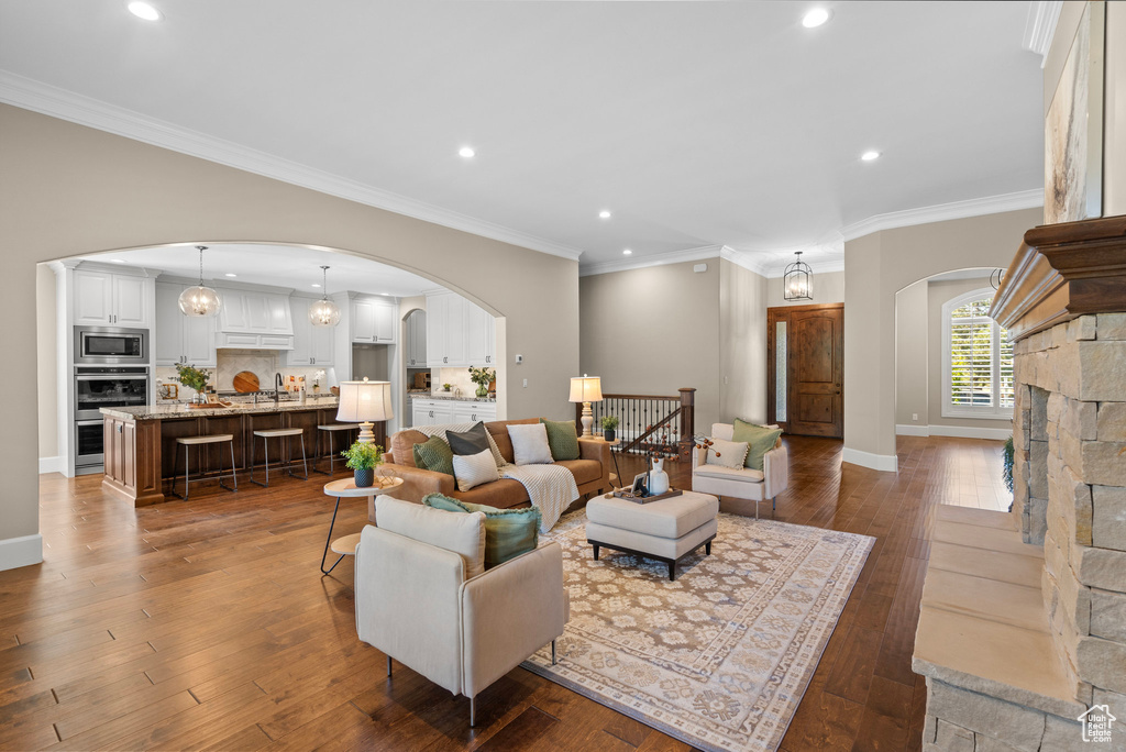 Living room with arched walkways, hardwood / wood-style floors, recessed lighting, and ornamental molding