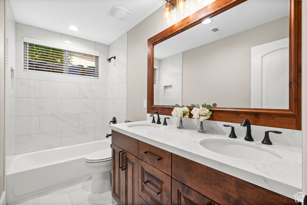 Full bathroom with shower / washtub combination, double vanity, marble look tile flooring, and recessed lighting