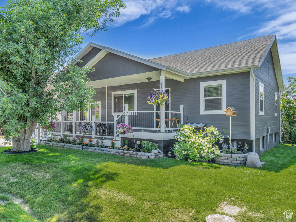 View of front facade featuring a shingled roof, a front lawn, and a porch