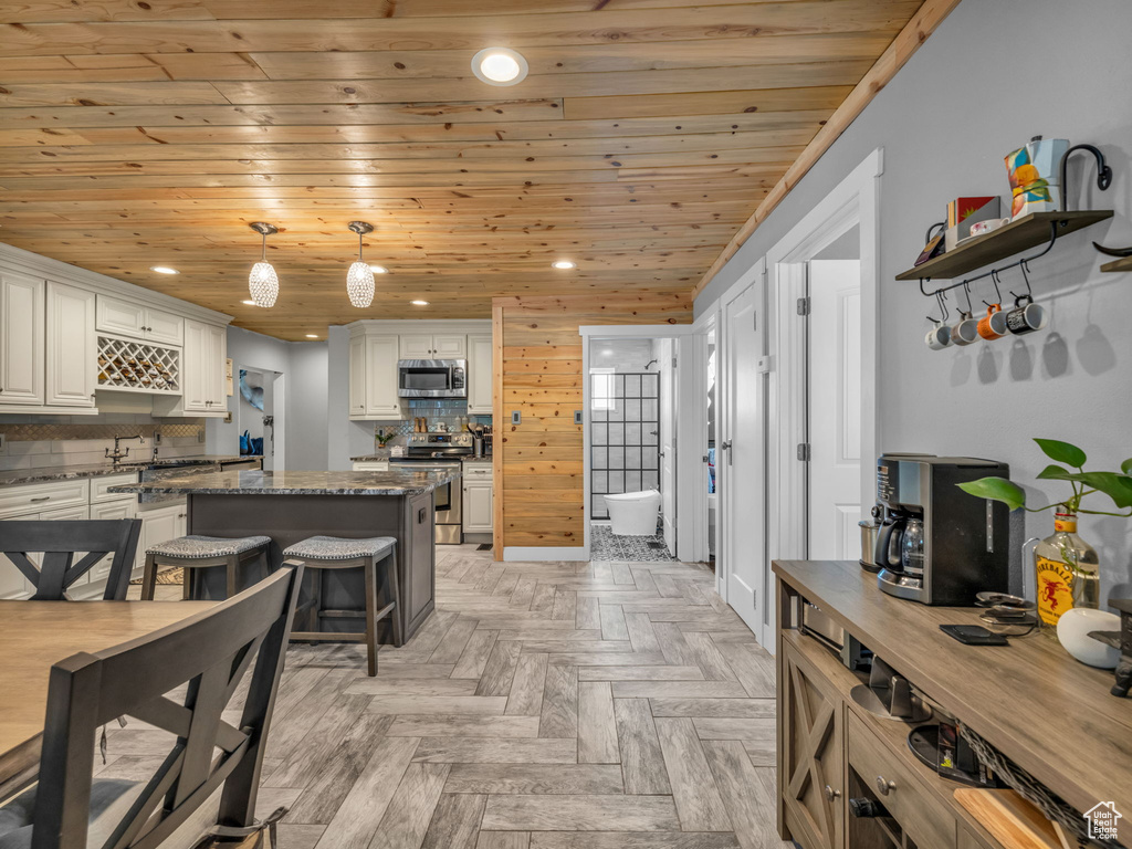 Kitchen featuring appliances with stainless steel finishes, a center island, wooden ceiling, backsplash, and recessed lighting