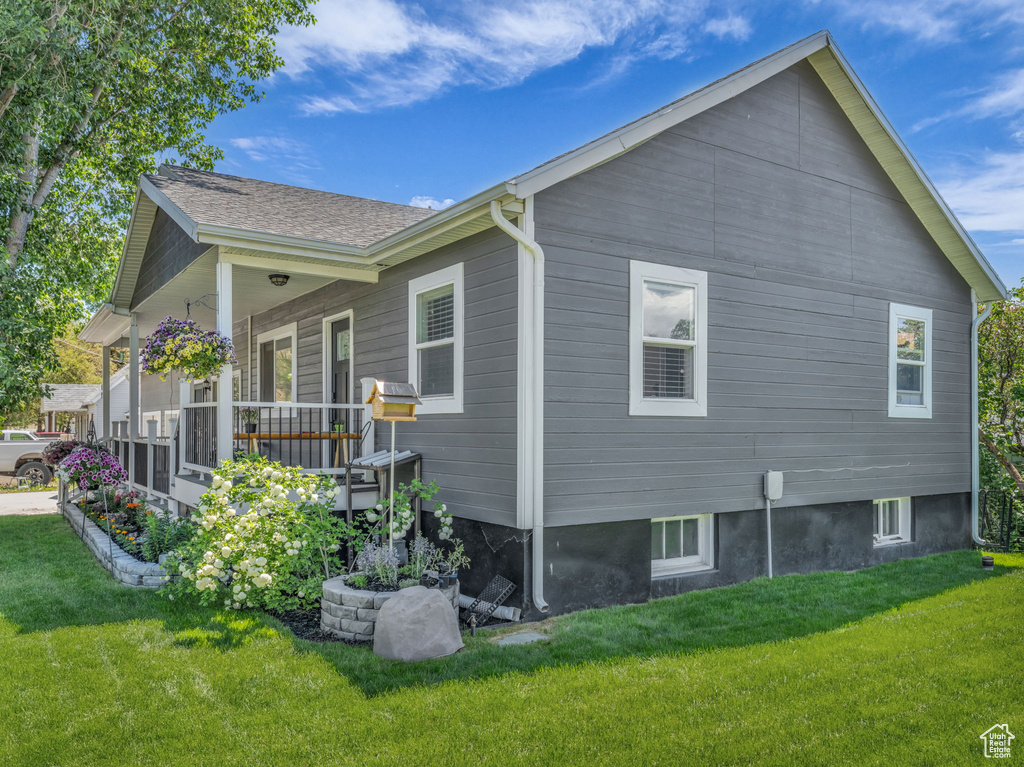 View of side of home with a lawn and covered porch