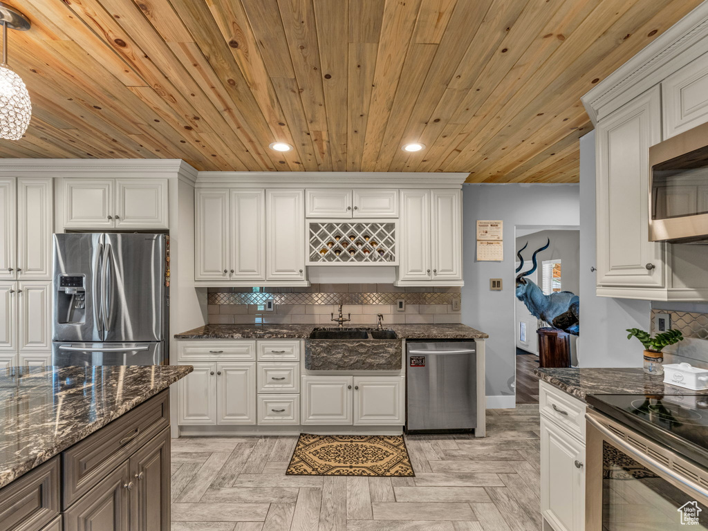 Kitchen with appliances with stainless steel finishes, wood ceiling, decorative backsplash, recessed lighting, and white cabinetry
