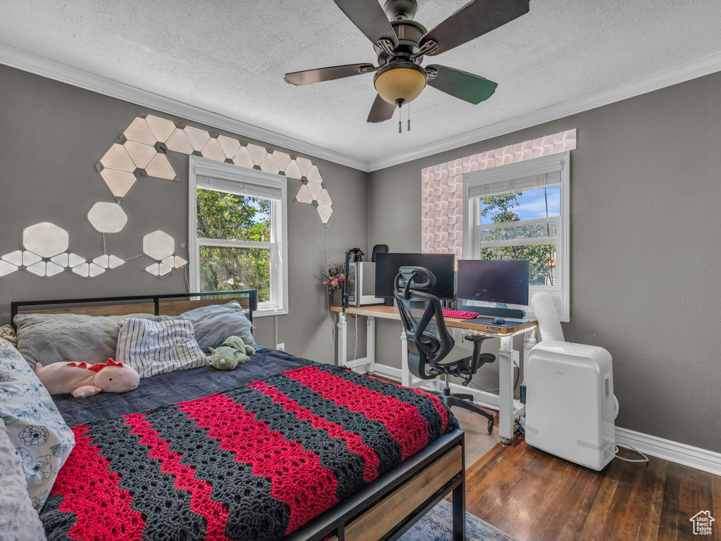Bedroom with wood finished floors, multiple windows, crown molding, a textured ceiling, and ceiling fan