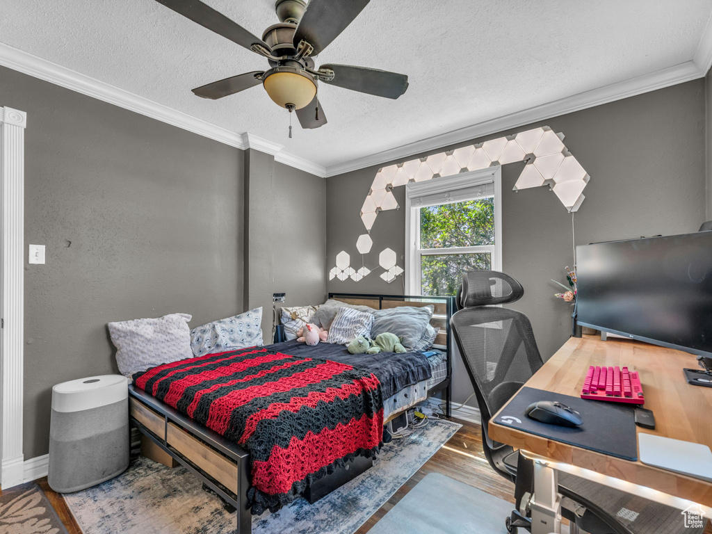 Bedroom featuring wood finished floors, crown molding, a desk, a ceiling fan, and a textured ceiling