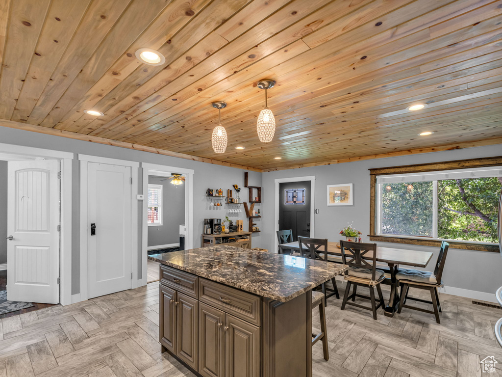 Kitchen featuring recessed lighting, a kitchen island, a kitchen bar, wooden ceiling, and pendant lighting