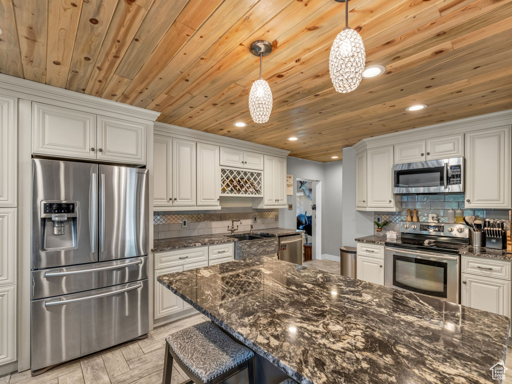 Kitchen with stainless steel appliances, recessed lighting, wood ceiling, decorative backsplash, and white cabinetry