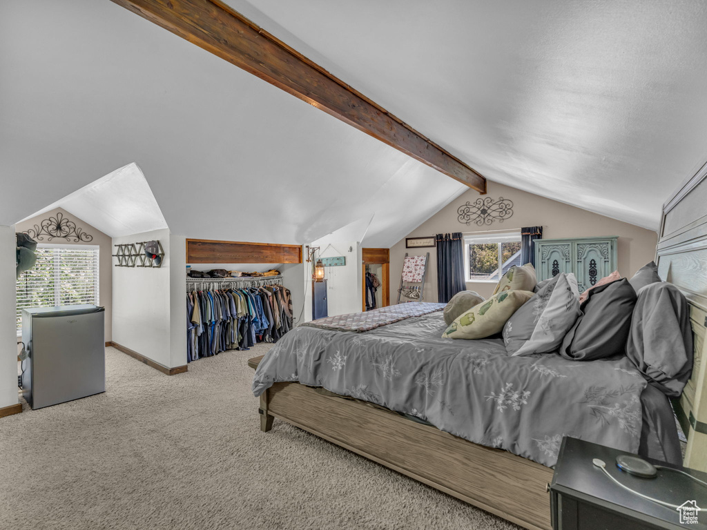 Carpeted bedroom featuring freestanding refrigerator and a closet