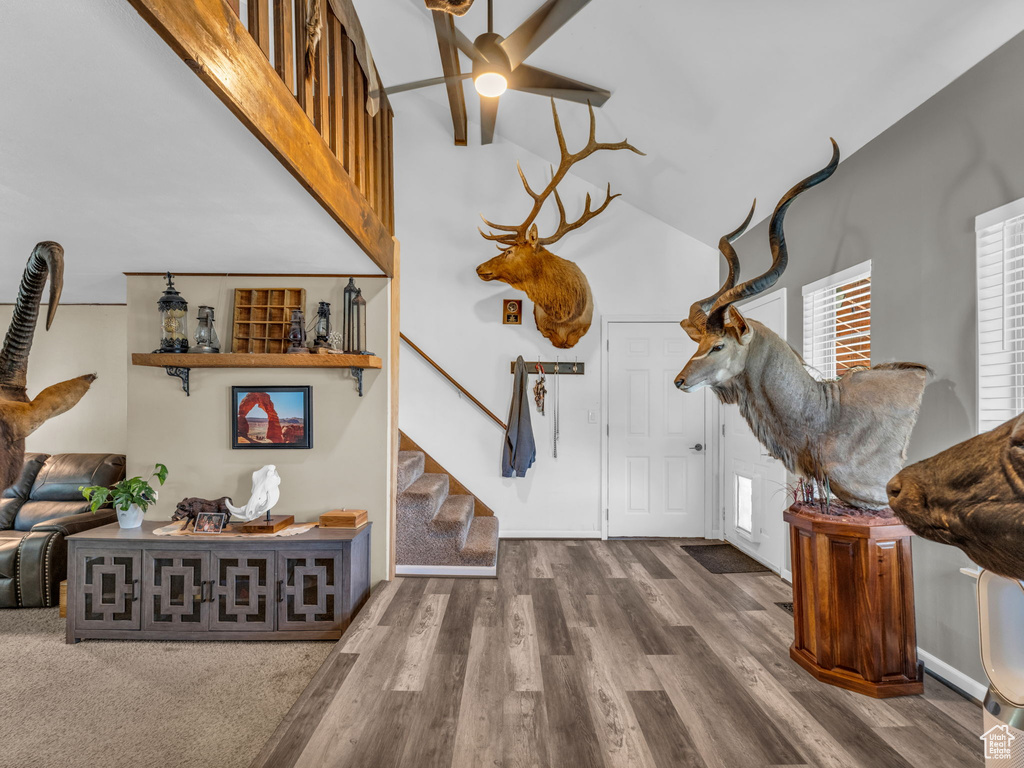 Living area with stairs, wood finished floors, high vaulted ceiling, and ceiling fan