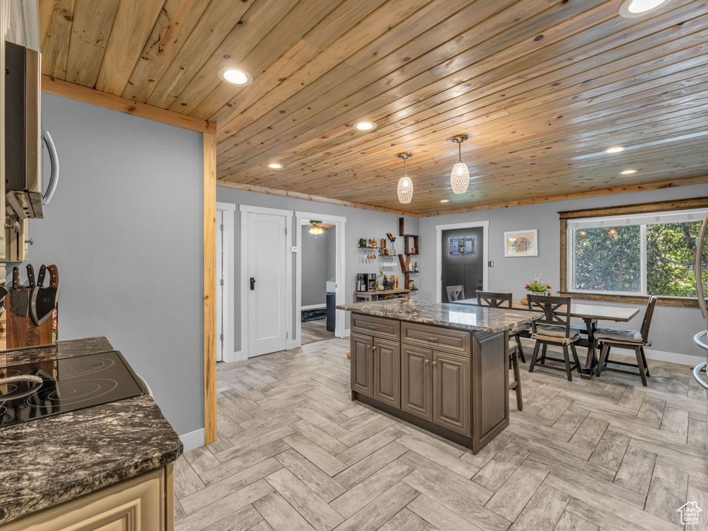 Kitchen with recessed lighting, wood ceiling, stainless steel microwave, dark stone counters, and pendant lighting