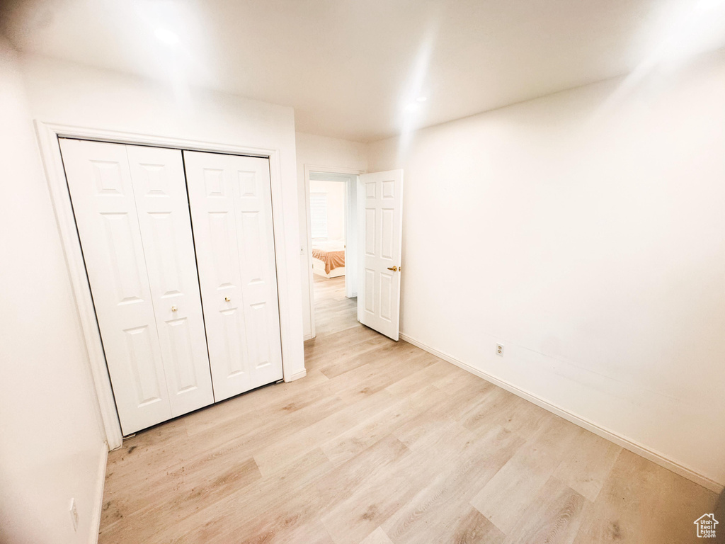 Unfurnished bedroom featuring light wood finished floors and a closet