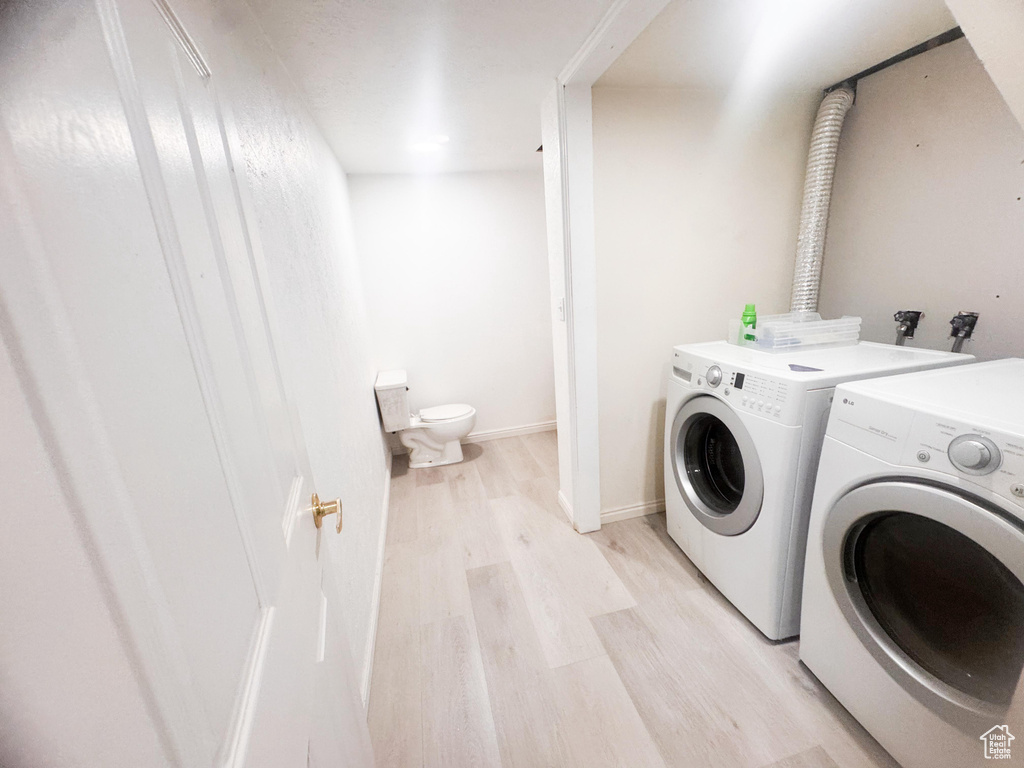 Laundry area with washer and clothes dryer and light wood-style floors