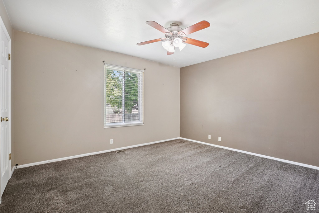 Carpeted empty room with ceiling fan and baseboards