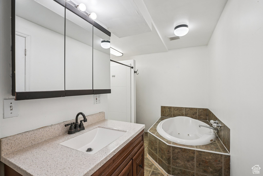 Full bathroom with a jetted tub, vanity, and a shower