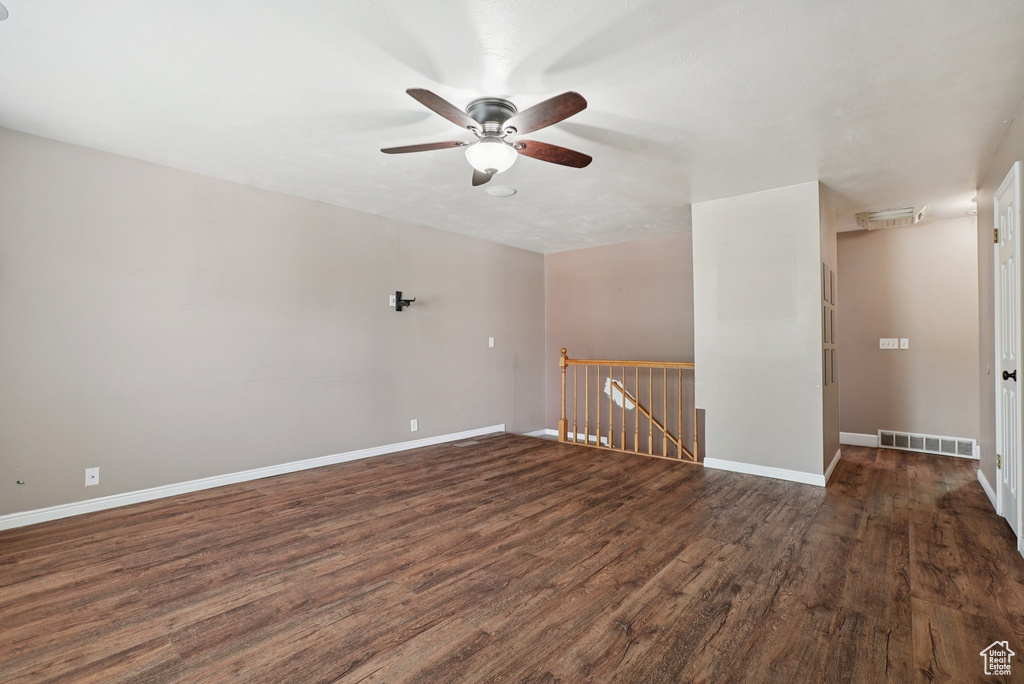 Unfurnished room featuring dark wood-style flooring and ceiling fan
