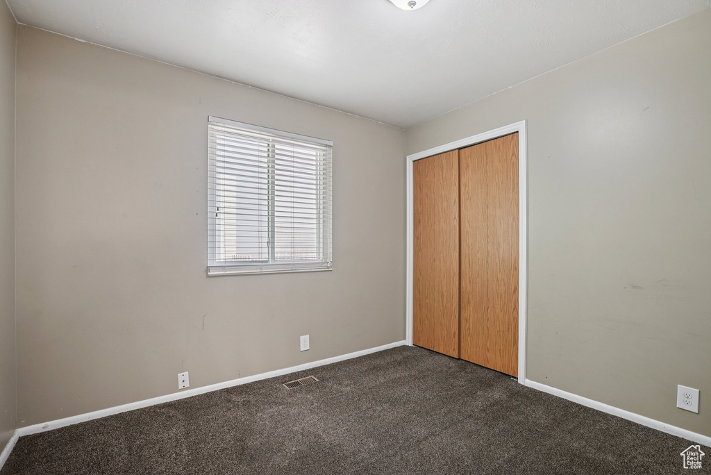Unfurnished bedroom with dark colored carpet and a closet