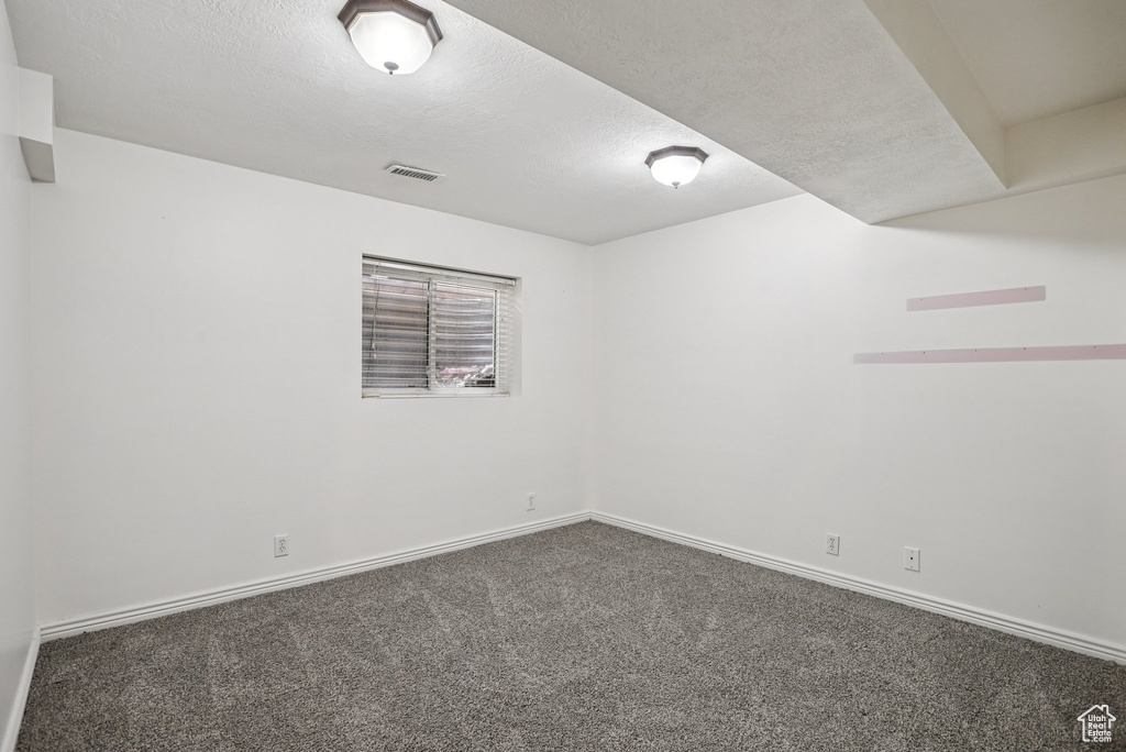 Unfurnished room with dark colored carpet and a textured ceiling