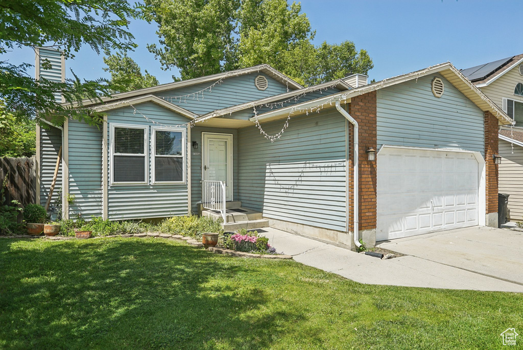Single story home featuring an attached garage, a front lawn, brick siding, and driveway