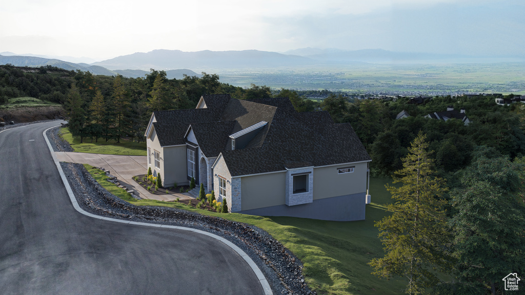 Aerial view of property and surrounding area featuring mountains and a forest