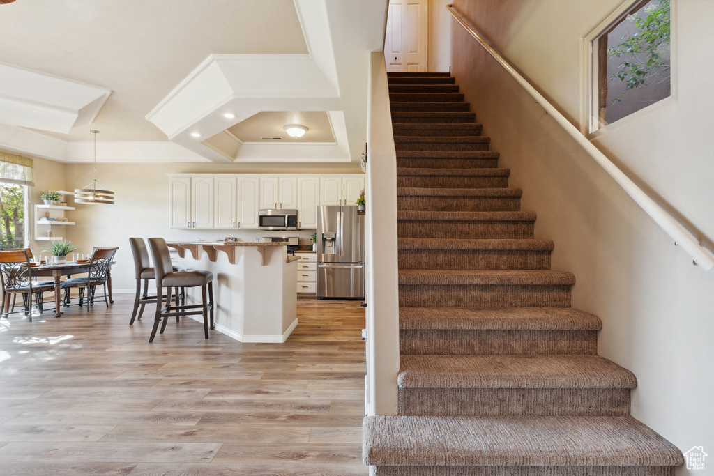 Stairway featuring wood finished floors, crown molding, and recessed lighting