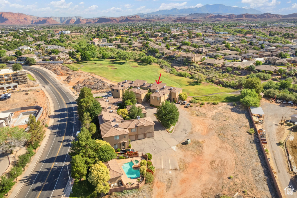 Aerial view of property and surrounding area featuring a mountainous background and nearby suburban area