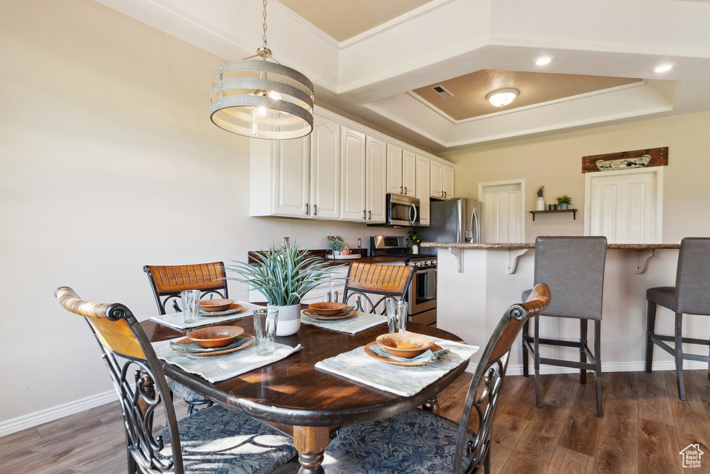 Dining area featuring dark wood-style floors, ornamental molding, and a tray ceiling