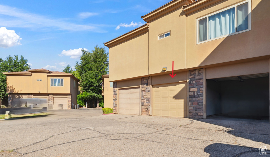 View of side of property featuring stone siding, stucco siding, and a garage