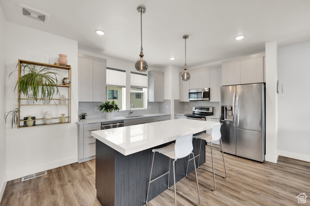Kitchen with stainless steel appliances, a sink, a kitchen bar, decorative backsplash, and recessed lighting