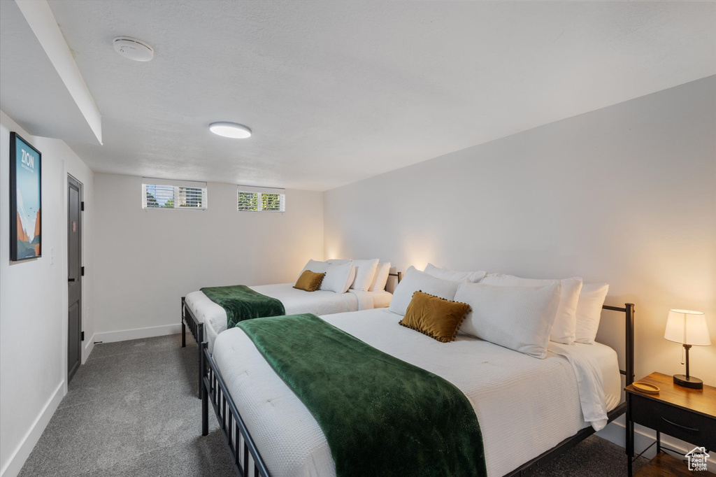 Bedroom featuring baseboards and dark carpet