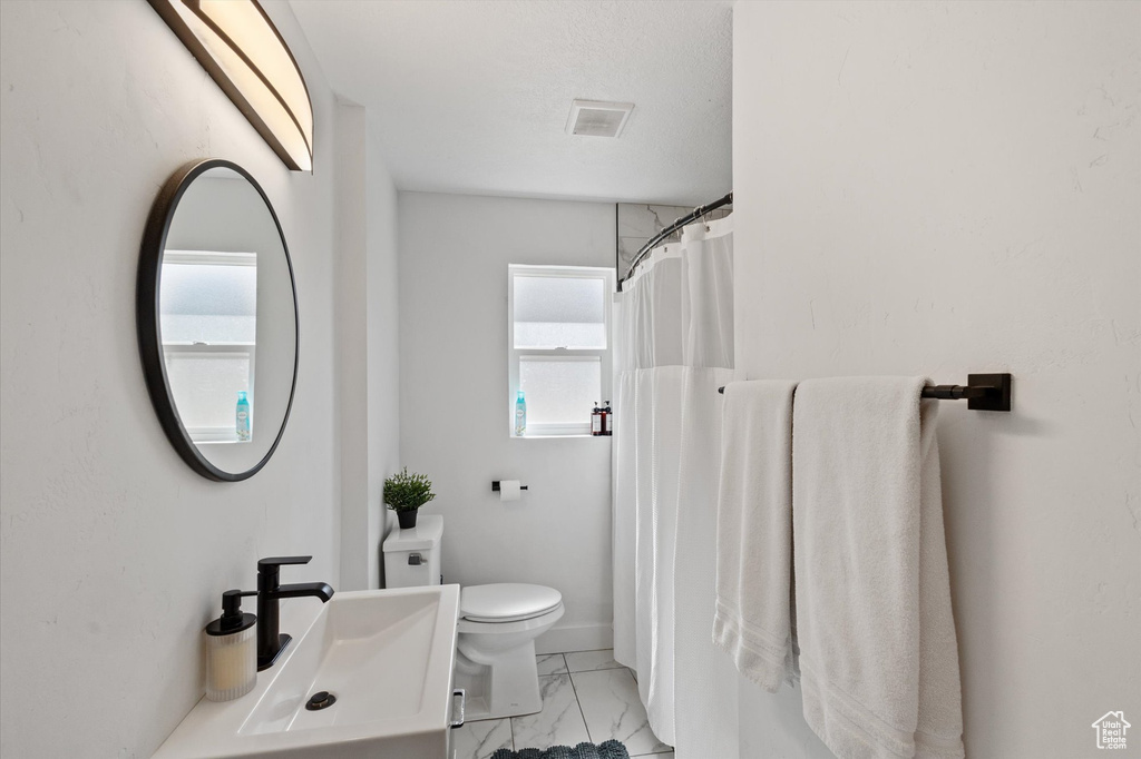Bathroom featuring marble finish floors and a shower with curtain