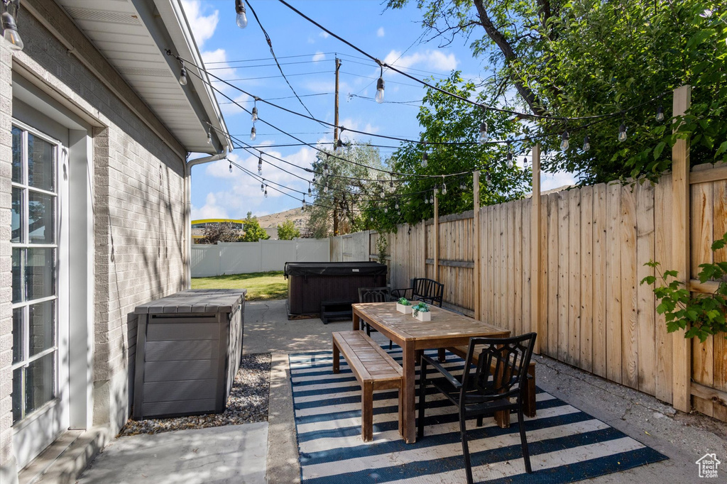 Fenced backyard featuring a hot tub, a patio, and outdoor dining space