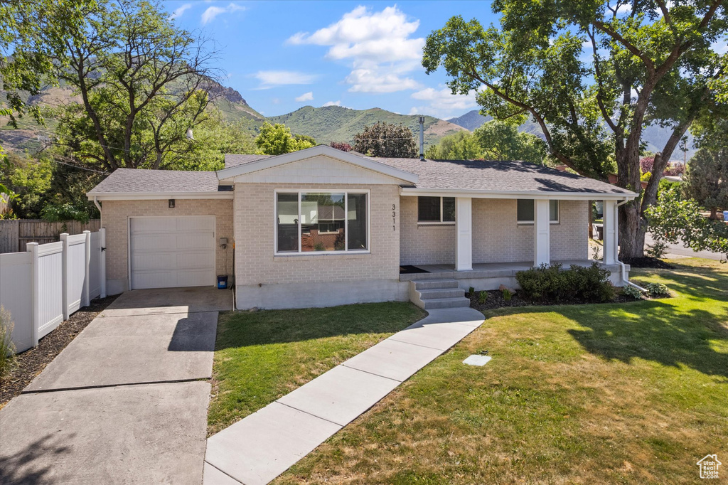 Ranch-style house featuring a garage, a mountain view, brick siding, covered porch, and concrete driveway