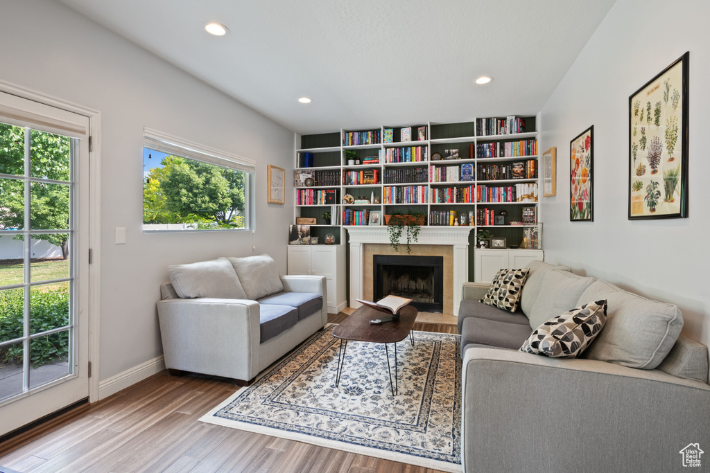 Living room with plenty of natural light, wood finished floors, baseboards, recessed lighting, and a fireplace with flush hearth