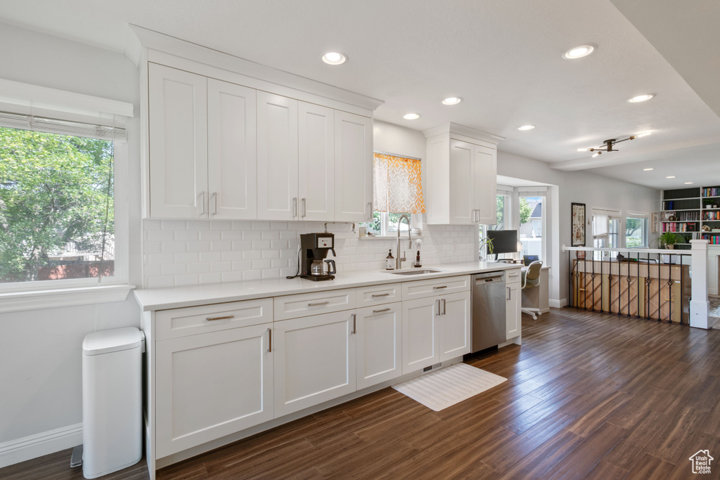 Kitchen with dishwasher, a sink, baseboards, backsplash, and white cabinets