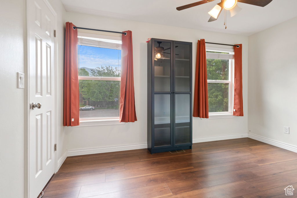 Spare room featuring a ceiling fan, dark wood-style floors, and baseboards