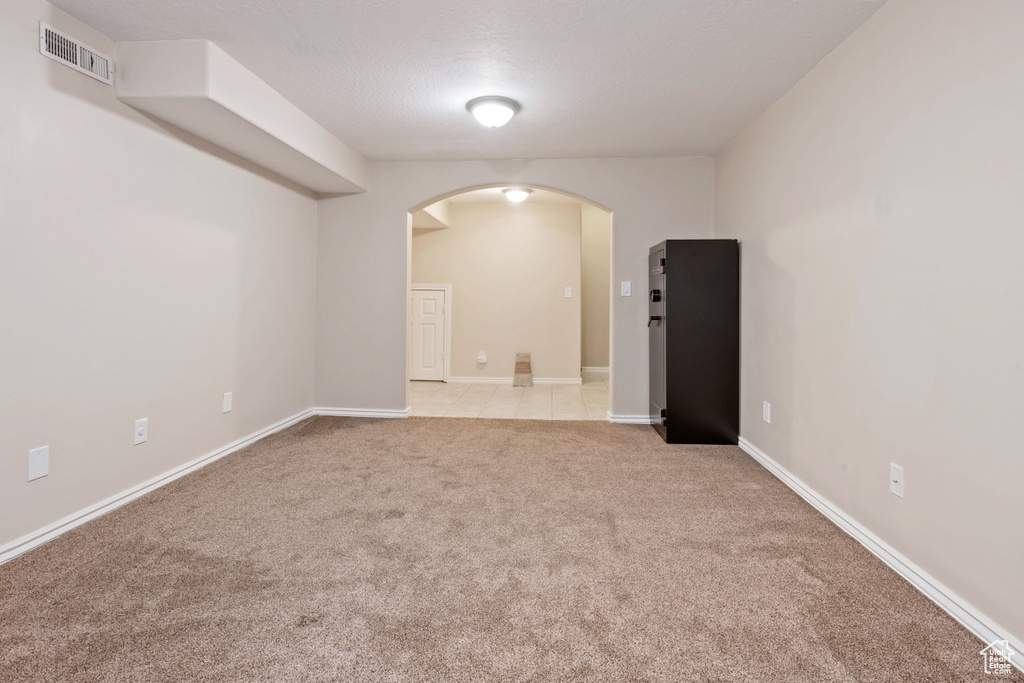 Spare room featuring arched walkways, light carpet, and baseboards